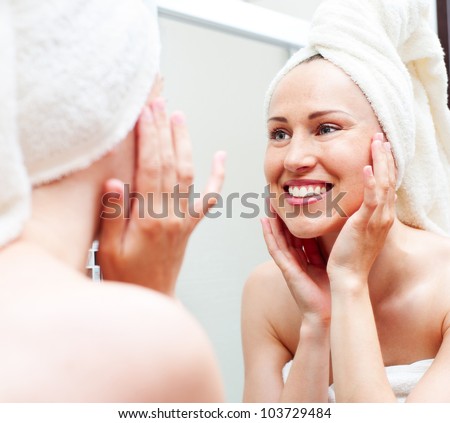 young smiley woman in towel looking in mirror