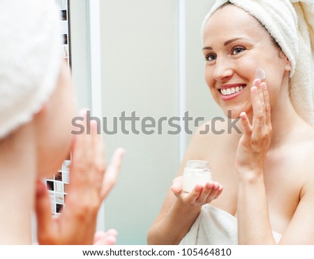 beautiful woman applying cream at the morning