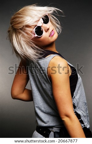 beautiful woman in sunglasses turning back. studio shot against dark background
