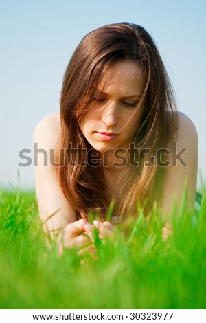 beautiful melancholy woman lying at the green grass