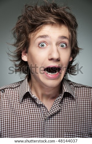 portrait of shocked guy against grey background