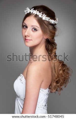 pretty woman with hairdo in white dress posing against grey background