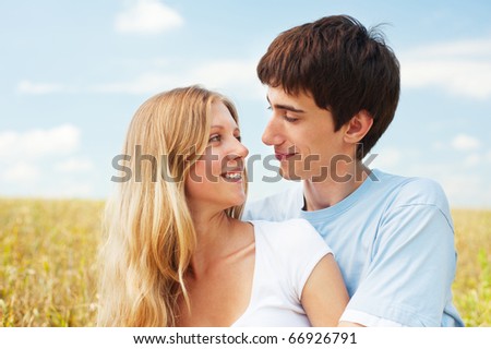 portrait of smiley couple over blue sky and yellow field