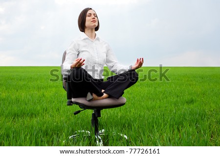 businesswoman sitting in lotus position on green field
