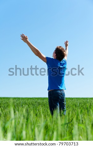 happy man in blue t-shirt standing on green meadow