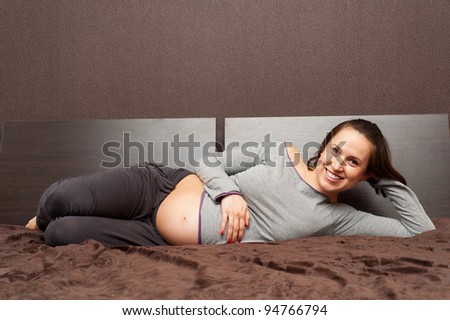 smiley pregnant woman lying on bed and relaxing