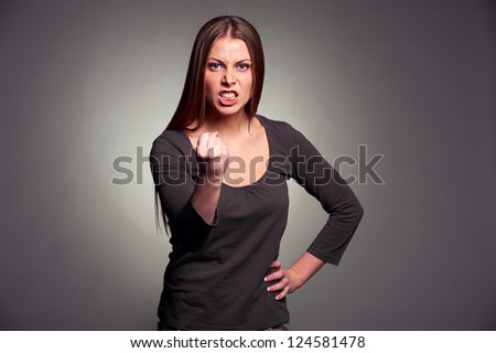 angry woman threatening the fist over grey background