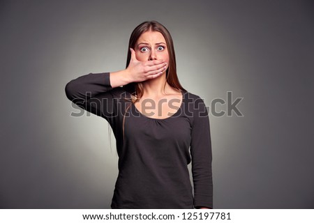 young adult woman holding hand over her mouth over grey background