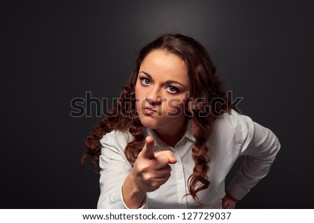 studio shot of angry woman pointing at camera. picture over dark background