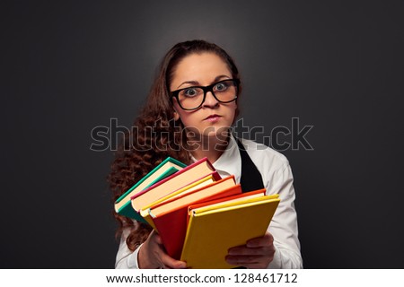 serious young woman in glasses offering books. picture over dark background