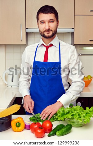 handsome man in formal wear preparing salad in the kitchen