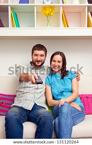 smiley young couple watching TV and resting