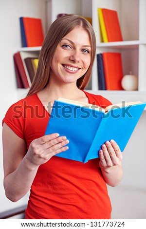 cheerful young woman holding the book and smiling