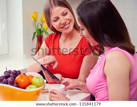 two smiley girls using tablet pc at home