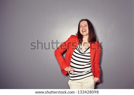 laughing brunette in red coat standing over dark background