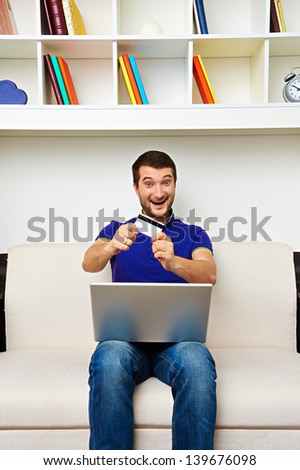 excited man holding laptop and credit card