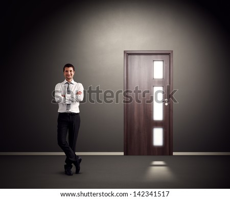 successful businessman standing against wall with door