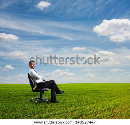 successful businessman sitting on field and resting