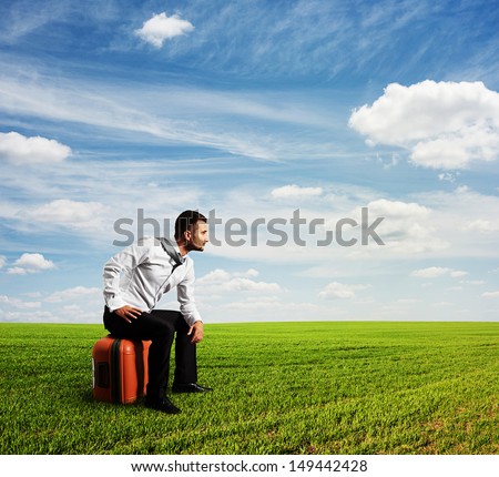 tired man sitting on his bag and looking into the distance
