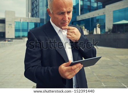 pensive businessman looking at tablet pc