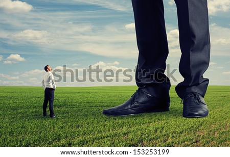 small businessman looking at his big boss. photo on green field