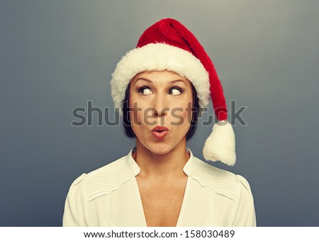 surprised young woman in red christmas hat over grey background