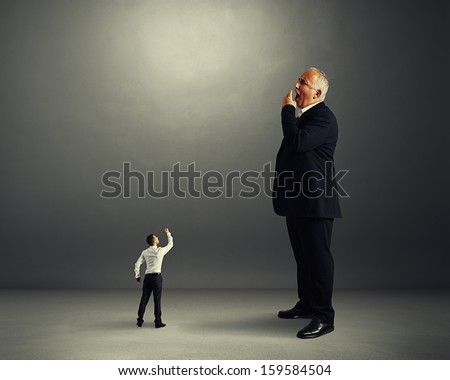 small man showing fist to big yawning businessman