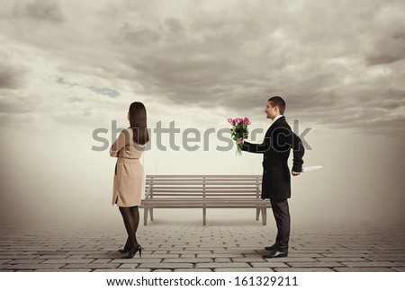 man holding behind the back knife and looking at young woman