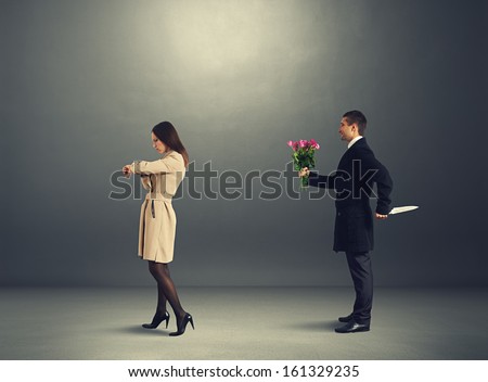 man with knife and flowers standing behind beautiful woman