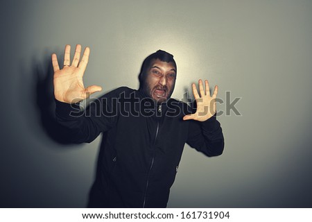criminal man screaming and raising hands up over grey background
