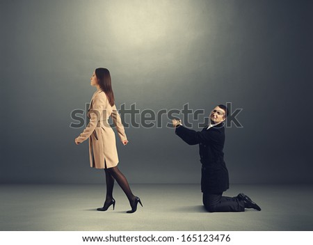 sad man bending the knee before outgoing woman in dark room