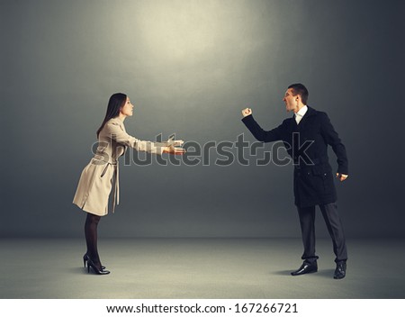 angry man at odds with young woman. photo in dark studio