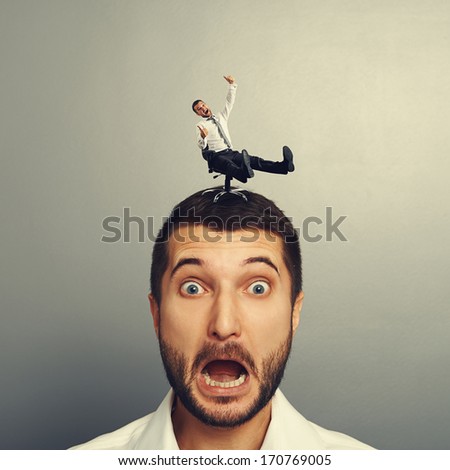 portrait of scared man with small crazy man on the head