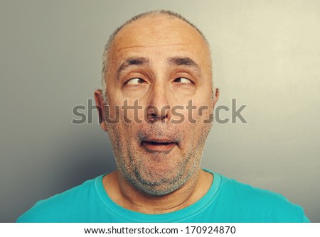 portrait of funny senior man in blue t-shirt over grey background