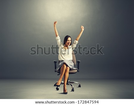 happy successful woman sitting on the chair and raising hands up