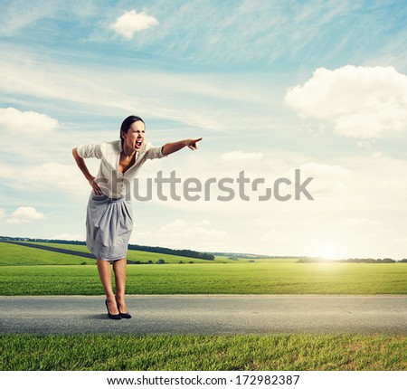 angry screaming woman standing on the road and pointing at something