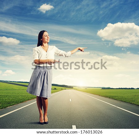 successful young woman pointing at something and smiling