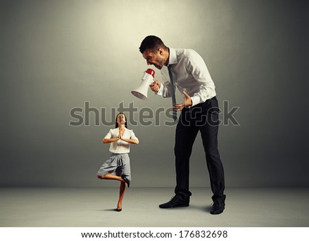 aggressive businessman screaming at small calm woman over dark background