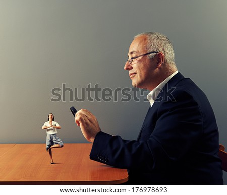 smiley businessman looking with magnifying glass at small meditation woman