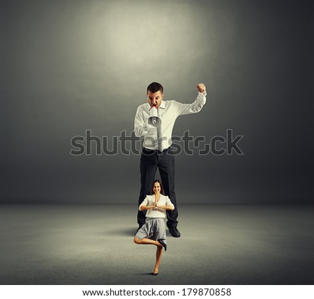 aggressive director screaming at small calm woman over dark background