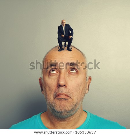 amazed man looking up at calm businessman on his head