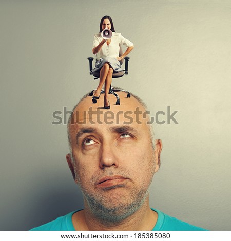 tired man and angry woman on his head over grey background