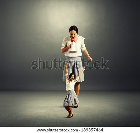 happy woman and angry big woman over dark background