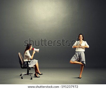 angry young woman screaming at calm woman over dark background