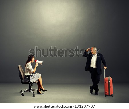senior man with case looking at screaming woman over dark background