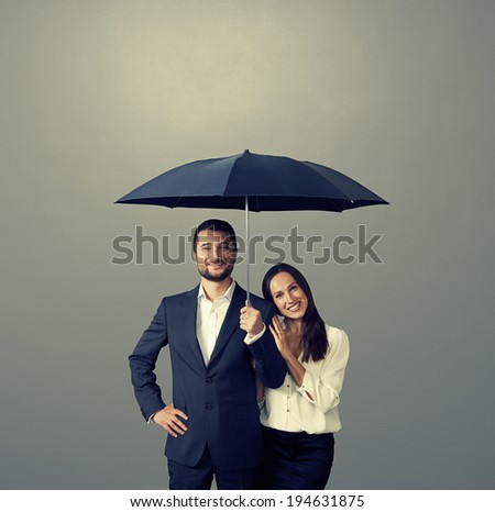 smiley couple under umbrella over dark background