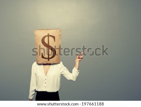 businesswoman with paper bag on her head pointing at empty grey copyspace