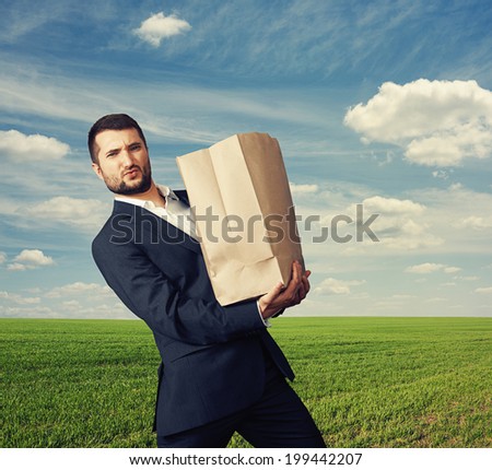 handsome man holding heavy paper bag at outdoor