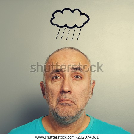portrait of depressed senior man with drawing storm cloud over grey background