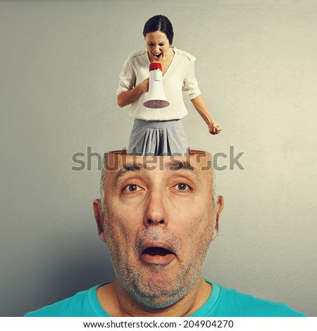 angry screaming woman in the head of amazed senior man over grey background